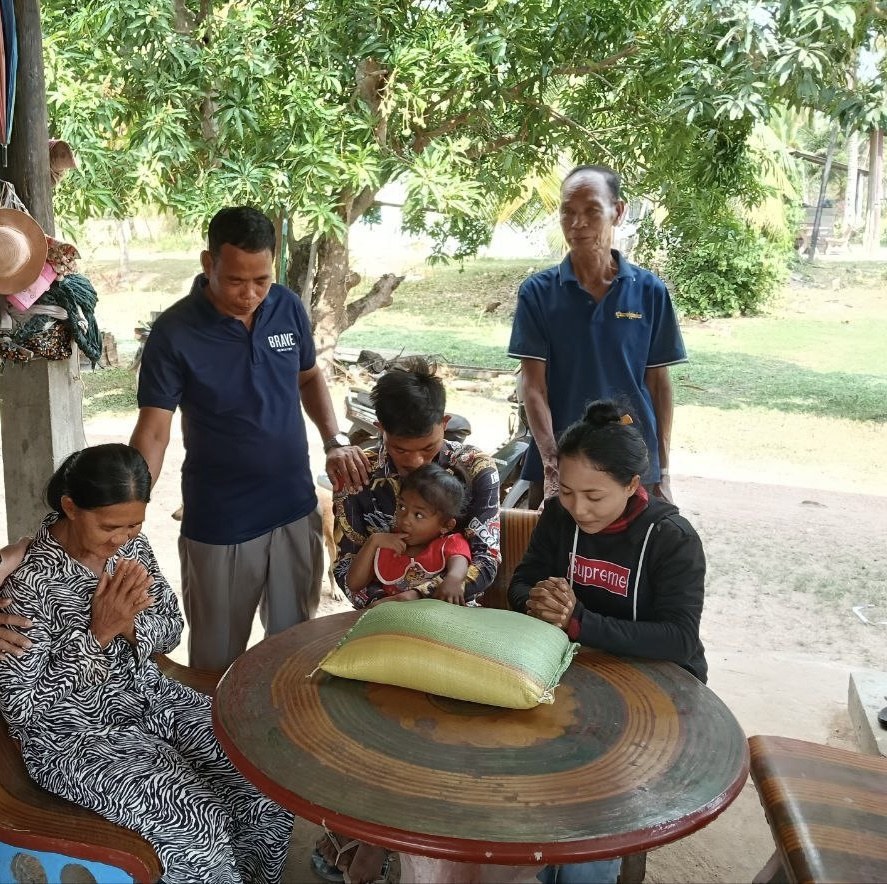 Praying with a family during a home visit in Chhuk