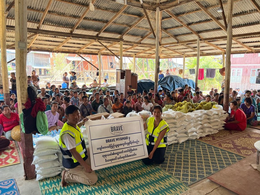 A family receiving relief supplies at their damaged home