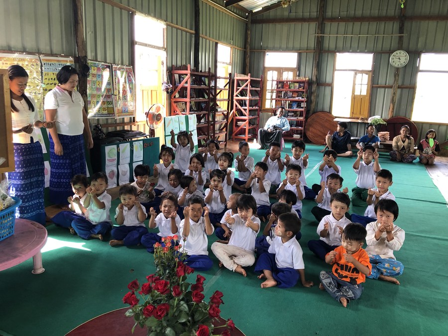 Grace Preschool children with their teachers in a classroom with bookshelves