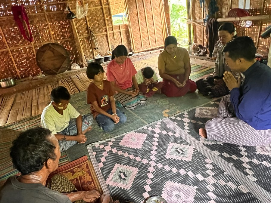 A pastor praying with a family in their home in Myanmar